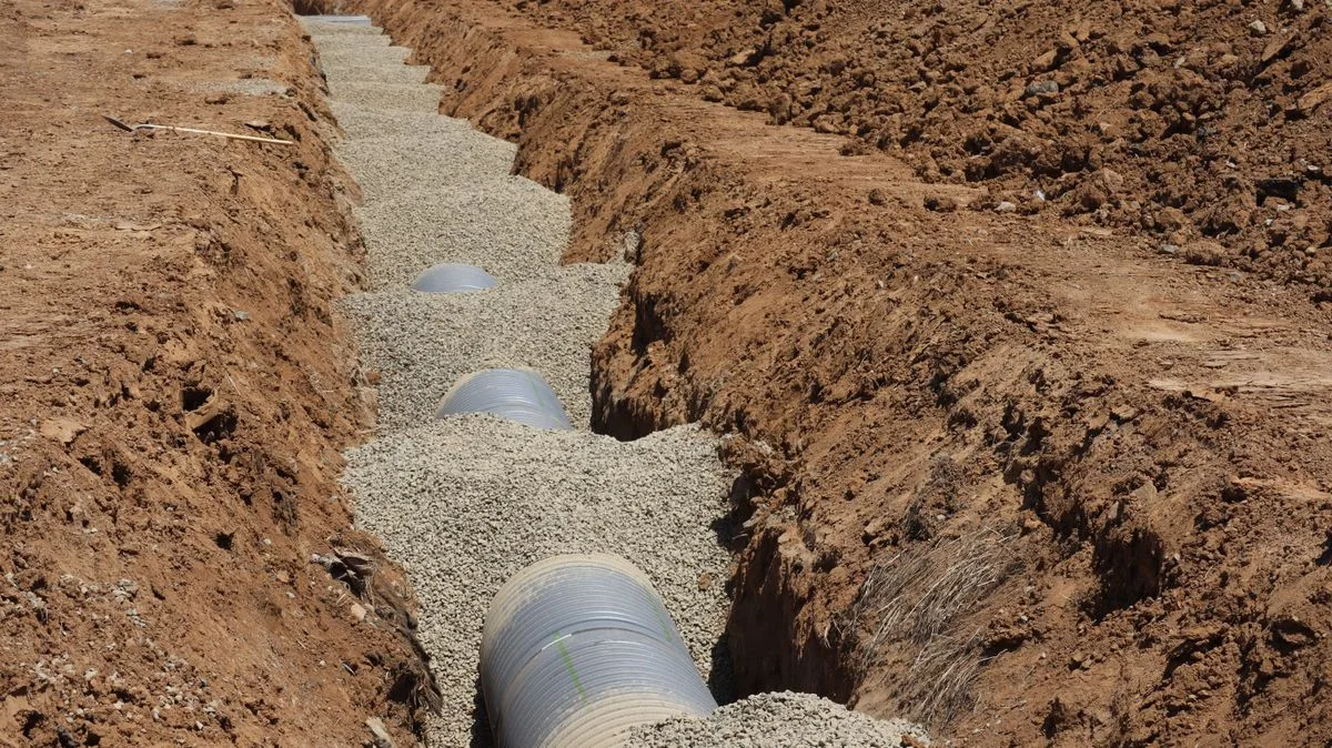 Drainage pipe construction in a gravel-filled trench showing french drain installation