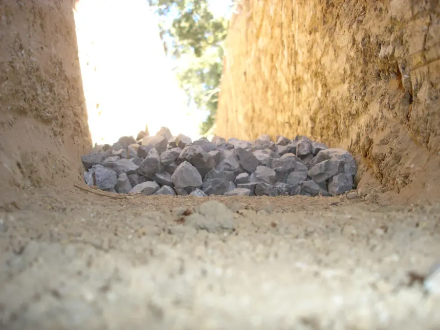 Clean angular drainage stone bedded in the base of an open French drain trench